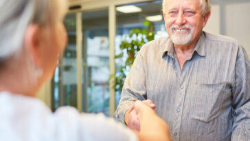 older man being greeted at service desk