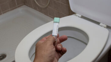 hand holding bowel cancer screening test in bathroom