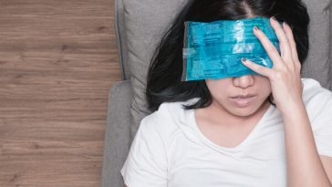 woman lying on couch with ice pack over eyes