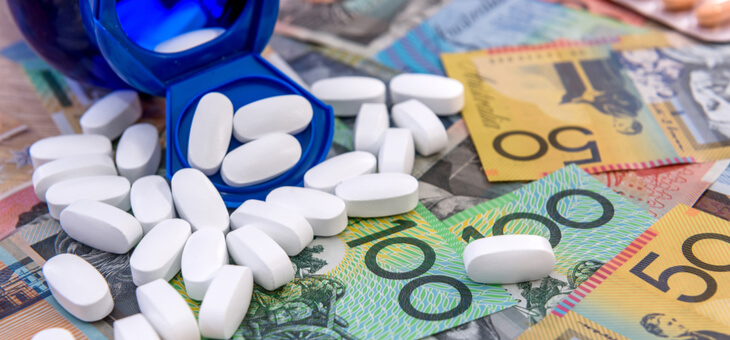 white pills spilling from blue bottle on to pile of australian cash