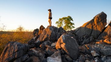 woman standing on large boulder in queensland outback