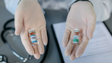 gloved hands holding two different covid vaccines