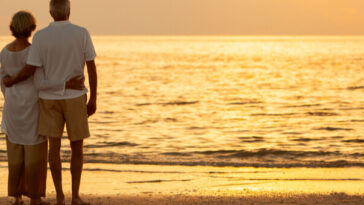 mature couple embracing on beach at sunset