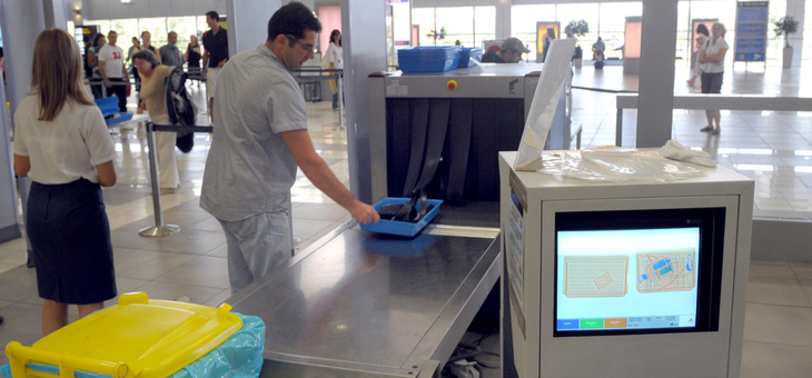 man placing belongings in airport security xray machine