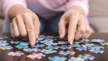 elderly woman doing jigsaw puzzle