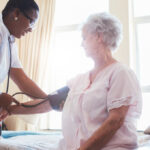 woman getting blood pressure measured by home nurse