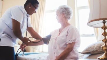 woman getting blood pressure measured by home nurse