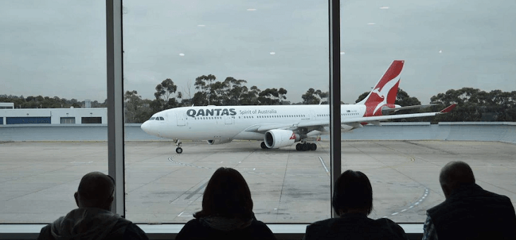 group of people in airport watching qantas plane taxiing