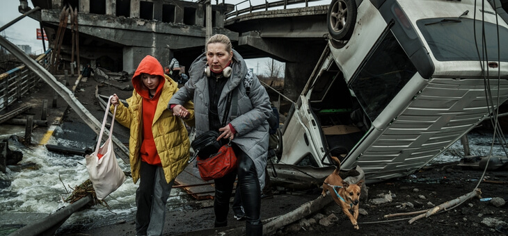 mother and young daughter fleeing from destroyed building in ukraine