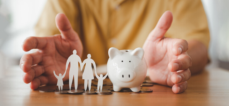 elderly man with piggy bank and paper cutout of family