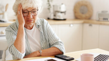 sad older woman paying bills on laptop