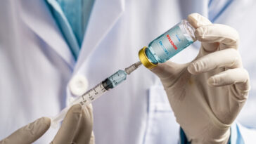 doctor drawing vaccine into syringe from vial