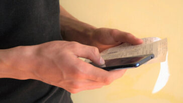 man calculating items on a receipt with phone