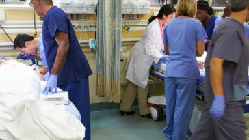 doctors and nurses in scrubs responding to patients in emergency room