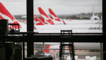 view of three qantas planes waiting at airport gates