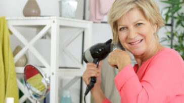 middle aged woman blow drying hair