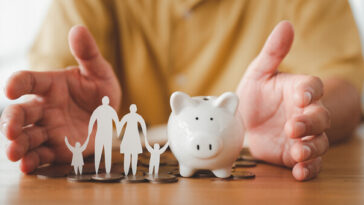 elderly man with piggy bank and paper cutout of family