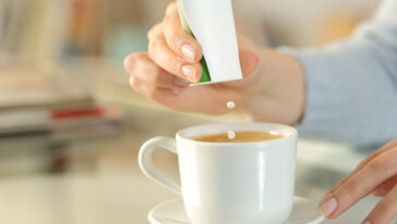 woman putting artificial sweetener in tea