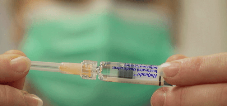 doctor in mask holding syringe of flu vaccine