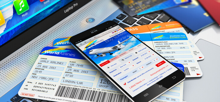plane tickets with phone on top displaying booking website