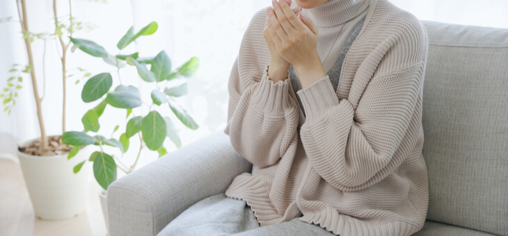 woman shivering on couch wearing thick woolen sweater