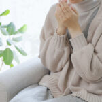 woman shivering on couch wearing thick woolen sweater