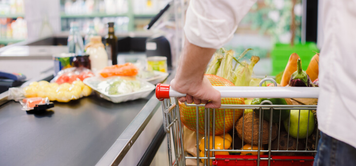 man placing items from trolley on supermarket checkout belt
