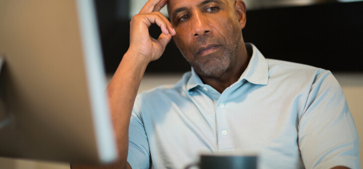middle aged man sitting at desk looking worried