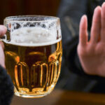 person holding up palm refusing glass of beer