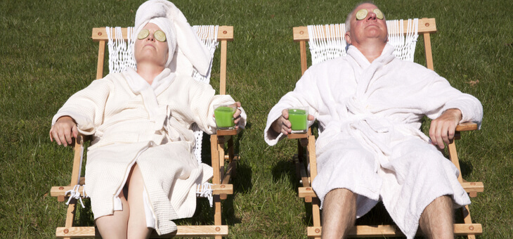 middle aged couple in bath robes relaxing in deck chairs