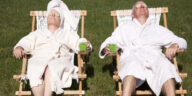 middle aged couple in bath robes relaxing in deck chairs