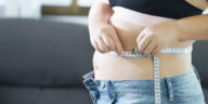 overweight woman measuring belly with tape measure