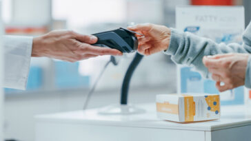woman paying for medicine at pharmacy with card
