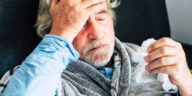 sick man wrapped in blanket holding tissue