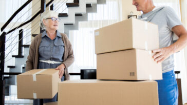 middle aged couple moving boxes into new home