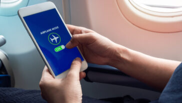 person on flight putting phone in airplane mode