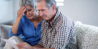 middle aged couple looking at bill with concern