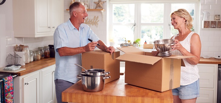 middle aged couple unpacking boxes in new home