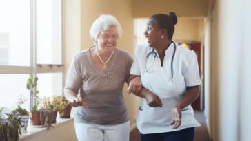 elderly woman walking arm in arm with nurse