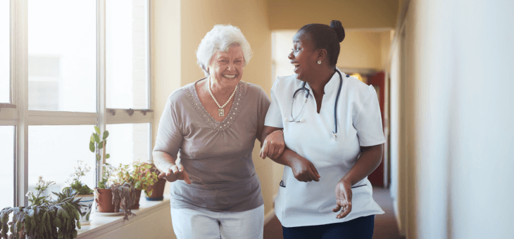 elderly woman walking arm in arm with nurse