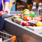 person placing items on supermarket checkout belt