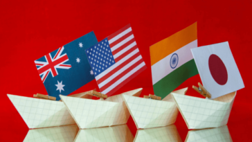 four paper boats bearing the flags of Australia, the US, India and Japan