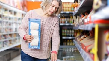 middle aged woman looking in supermarket freezer