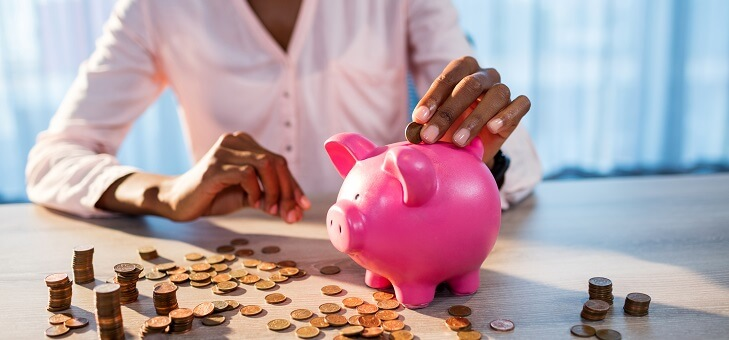 woman placing coins in piggy bank