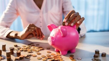 woman placing coins in piggy bank