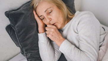 woman lying sick on couch coughing