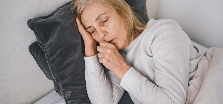 woman lying sick on couch coughing