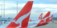 tails of three qantas planes at airport