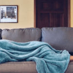 sick person on couch under blanket