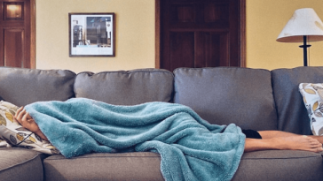 sick person on couch under blanket